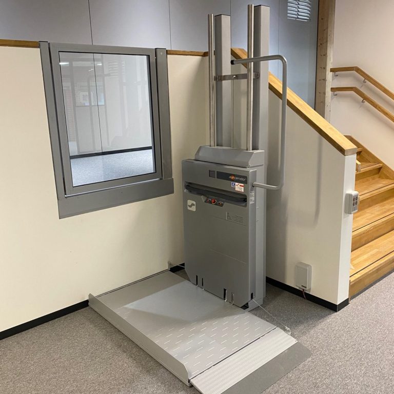 Treppenlift neben einer Wand, mit einer Plattform und zwei vertikalen Stangen in löhne