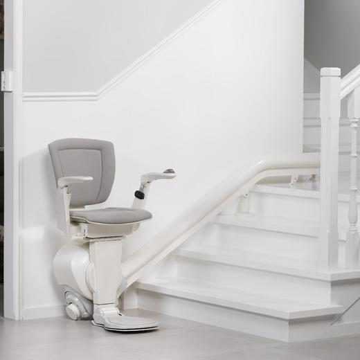 Treppenlift auf einer geraden, weißen Treppe mit grauem Sitz in Minden